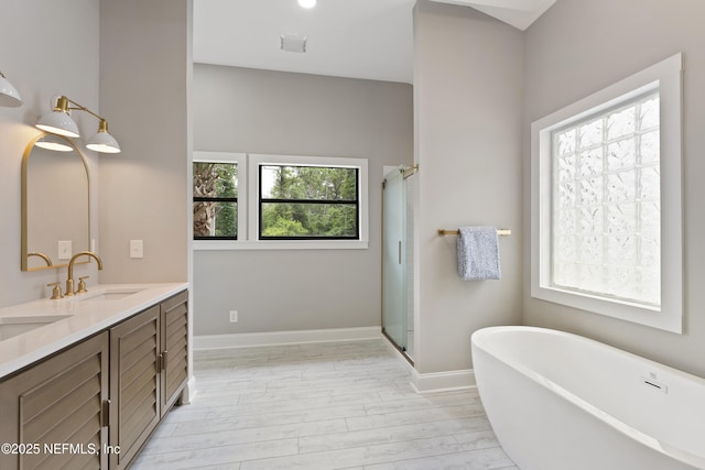 1381 Forrest Dr, Fernandina Beach, FL 32034 - full bathroom featuring a freestanding bath, double vanity, a shower stall, wood finished floors, and baseboards