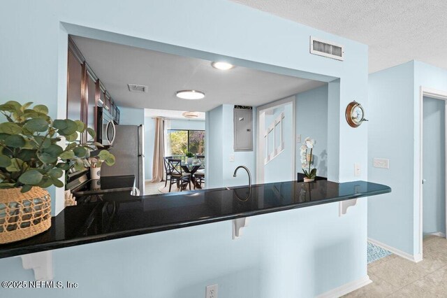 3145 Coastal Hwy Unit 1162, Saint Augustine, FL 32084 - kitchen with stainless steel appliances, dark countertops, a breakfast bar area, a peninsula, and a sink