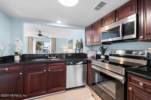 3145 Coastal Hwy Unit 1162, Saint Augustine, FL 32084 - kitchen featuring appliances with stainless steel finishes, a sink, dark countertops, and reddish brown cabinets
