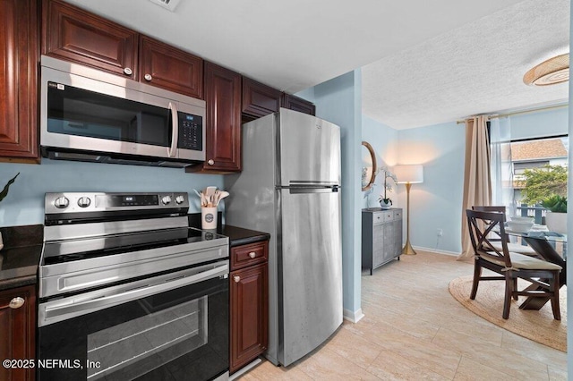 3145 Coastal Hwy Unit 1162, Saint Augustine, FL 32084 - kitchen featuring stainless steel appliances, baseboards, dark countertops, and a textured ceiling
