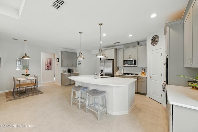 95362 Cornflower Dr, Fernandina Beach, FL 32034 - kitchen with gray cabinetry, appliances with stainless steel finishes, an island with sink, recessed lighting, and light countertops
