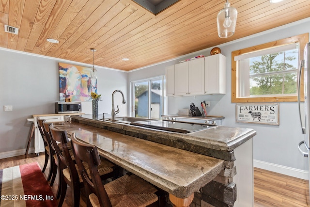 97150 Caravel Trl, Yulee, FL 32097 - kitchen featuring wood ceiling, stainless steel microwave, baseboards, light wood finished floors, and white cabinetry