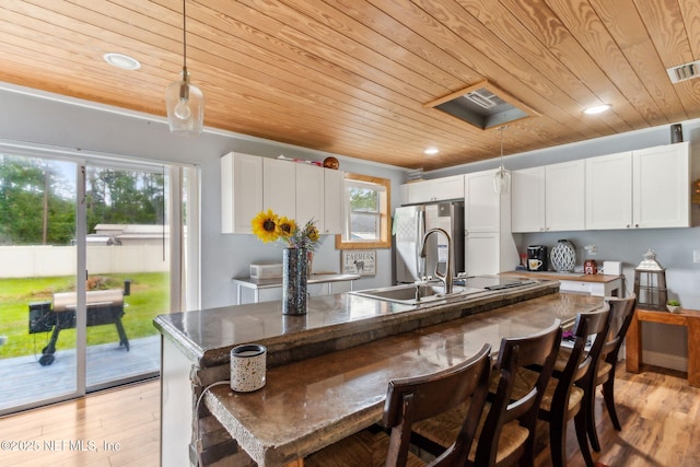 97150 Caravel Trl, Yulee, FL 32097 - kitchen with wood ceiling, freestanding refrigerator, white cabinets, light wood-style flooring, and a kitchen breakfast bar