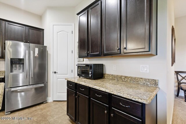 46 Gabacho Ct, Saint Augustine, FL 32095 - kitchen with stainless steel fridge with ice dispenser, light tile patterned floors, dark brown cabinets, and light stone counters