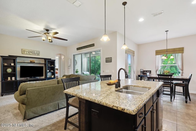 46 Gabacho Ct, Saint Augustine, FL 32095 - kitchen featuring arched walkways, a ceiling fan, an island with sink, decorative light fixtures, and light stone counters