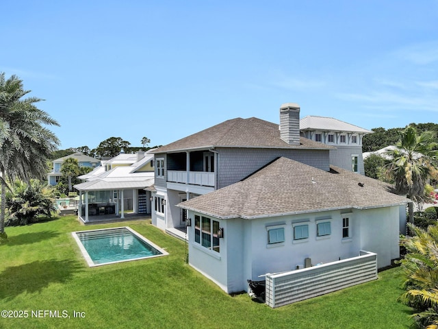 532 Atlantic Beach Ct, Atlantic Beach, FL 32233 - rear view of house with a balcony, a shingled roof, an outdoor pool, a chimney, and a yard