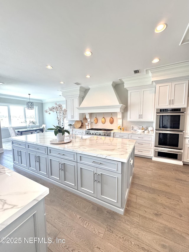 532 Atlantic Beach Ct, Atlantic Beach, FL 32233 - kitchen featuring custom range hood, gray cabinetry, stainless steel double oven, ornamental molding, and a large island