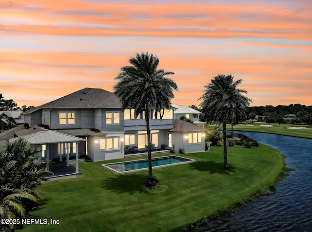 532 Atlantic Beach Ct, Atlantic Beach, FL 32233 - back of property at dusk with a water view, a yard, an outdoor pool, a patio, and roof with shingles