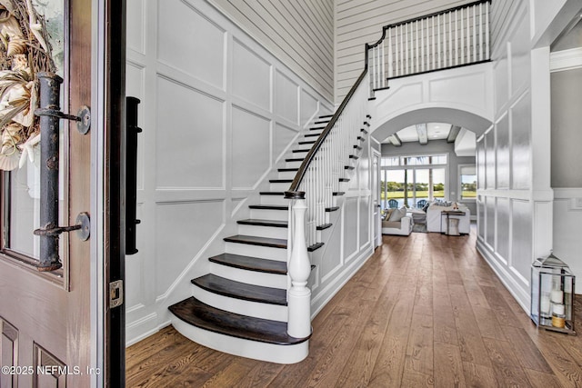 532 Atlantic Beach Ct, Atlantic Beach, FL 32233 - entrance foyer with a decorative wall, arched walkways, wood-type flooring, stairs, and a high ceiling