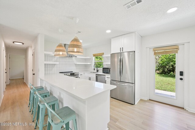 2619 Montreal St, Jacksonville, FL 32233 - kitchen with appliances with stainless steel finishes, a peninsula, light countertops, white cabinetry, and light wood-style flooring