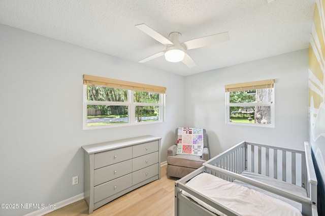2619 Montreal St, Jacksonville, FL 32233 - bedroom featuring light wood-type flooring, a nursery area, a textured ceiling, and ceiling fan