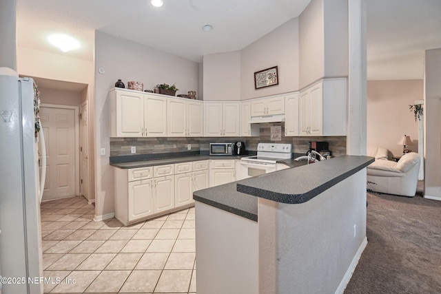 10121 SW 61st Terrace Rd, Ocala, FL 34476 - kitchen with white appliances, dark countertops, under cabinet range hood, decorative backsplash, and a towering ceiling