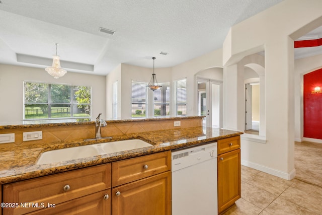 3975 Royal Pines Dr, Orange Park, FL 32065 - kitchen with white dishwasher, brown cabinetry, light stone countertops, light tile patterned floors, and pendant lighting
