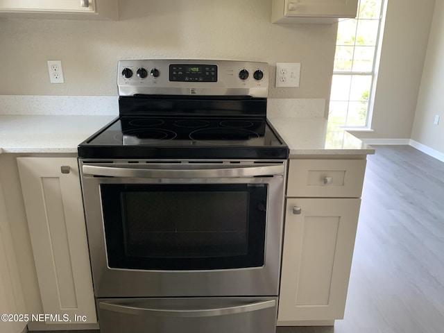 10961 Burnt Mill Rd Unit 917, Jacksonville, FL 32256 - kitchen featuring stainless steel electric range oven, wood finished floors, white cabinets, and light stone counters