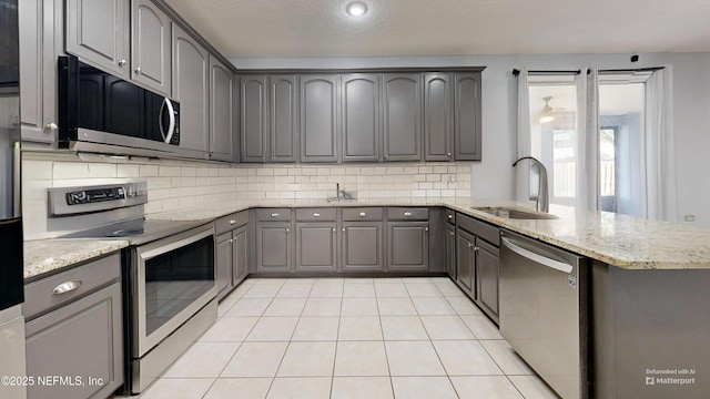 2032 Trailing Pines Way, Fleming Island, FL 32003 - kitchen with appliances with stainless steel finishes, gray cabinets, a sink, tasteful backsplash, and light stone countertops
