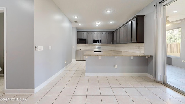 2032 Trailing Pines Way, Fleming Island, FL 32003 - kitchen featuring a peninsula, light stone countertops, a breakfast bar area, recessed lighting, and light tile patterned floors