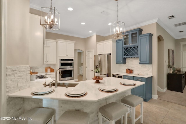 528 Sebastian Sq, Saint Augustine, FL 32095 - kitchen with stainless steel appliances, a chandelier, blue cabinets, a peninsula, and crown molding