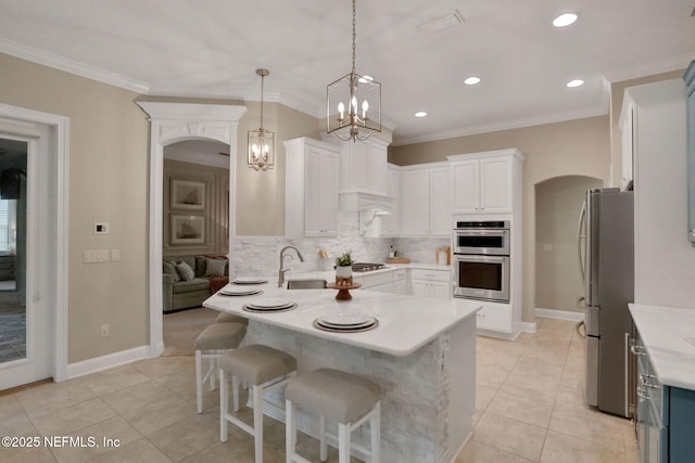 528 Sebastian Sq, Saint Augustine, FL 32095 - kitchen featuring stainless steel appliances, a peninsula, arched walkways, light countertops, and crown molding