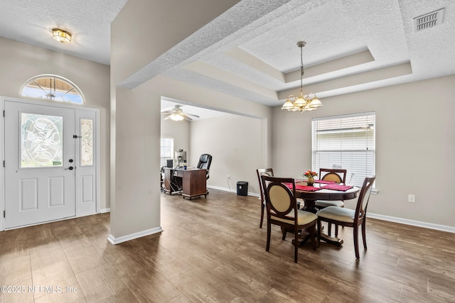 1861 Heartpine Dr, Middleburg, FL 32068 - dining area featuring a textured ceiling, baseboards, dark wood-style flooring, a chandelier, and a tray ceiling