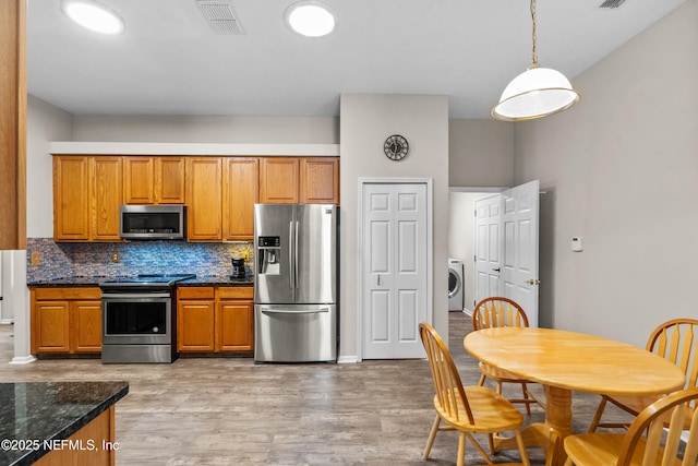 1861 Heartpine Dr, Middleburg, FL 32068 - kitchen featuring stainless steel appliances, washer / clothes dryer, decorative backsplash, light wood finished floors, and pendant lighting