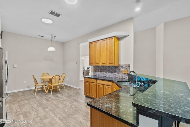 1861 Heartpine Dr, Middleburg, FL 32068 - kitchen featuring a sink, light wood finished floors, dark stone counters, baseboards, and freestanding refrigerator