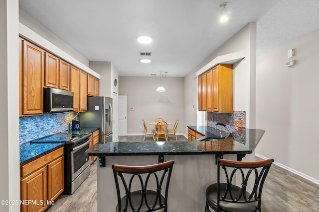 1861 Heartpine Dr, Middleburg, FL 32068 - kitchen with appliances with stainless steel finishes, light wood-type flooring, a peninsula, backsplash, and a breakfast bar area