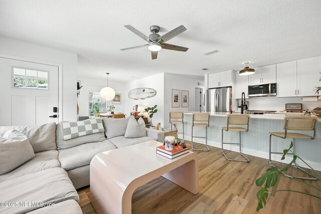 1848 Forsyth Ct, Atlantic Beach, FL 32233 - living area featuring light wood finished floors, ceiling fan, and a textured ceiling