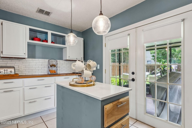 11461 Willet Ct S, Jacksonville, FL 32225 - kitchen with light tile patterned flooring, white cabinetry, decorative backsplash, hanging light fixtures, and a textured ceiling
