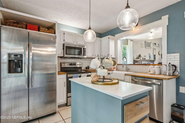 11461 Willet Ct S, Jacksonville, FL 32225 - kitchen featuring appliances with stainless steel finishes, decorative backsplash, white cabinetry, light tile patterned floors, and a center island