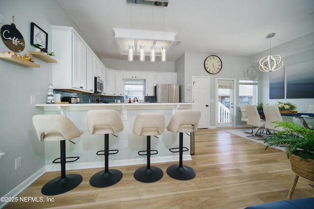 126 1st St S, Jacksonville Beach, FL 32250 - kitchen featuring appliances with stainless steel finishes, a chandelier, light wood-style flooring, and white cabinetry