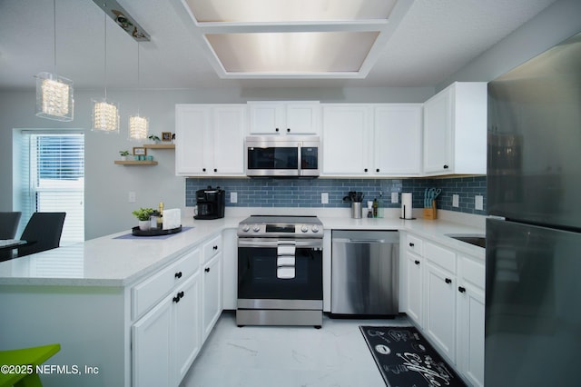 126 1st St S, Jacksonville Beach, FL 32250 - kitchen featuring appliances with stainless steel finishes, a peninsula, light countertops, and white cabinetry