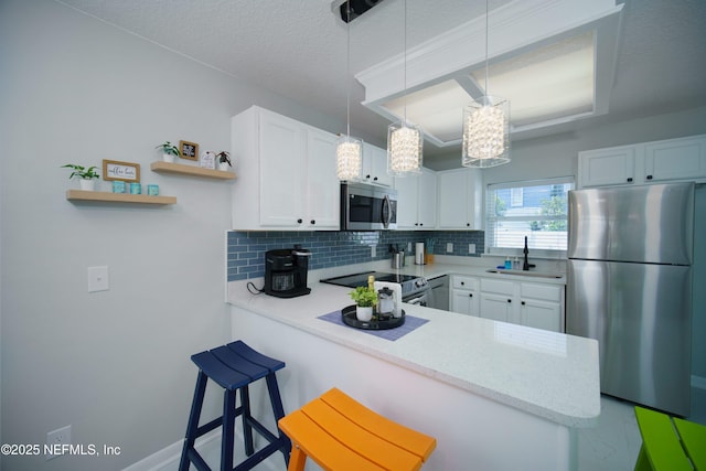 126 1st St S, Jacksonville Beach, FL 32250 - kitchen with stainless steel appliances, a sink, a peninsula, decorative backsplash, and white cabinetry