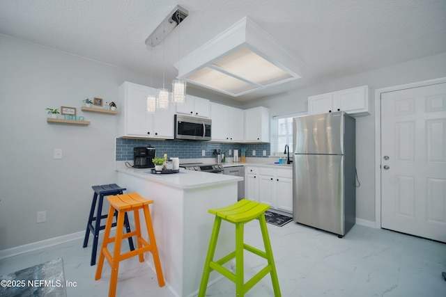 126 1st St S, Jacksonville Beach, FL 32250 - kitchen featuring stainless steel appliances, a peninsula, a kitchen bar, white cabinets, and a textured ceiling