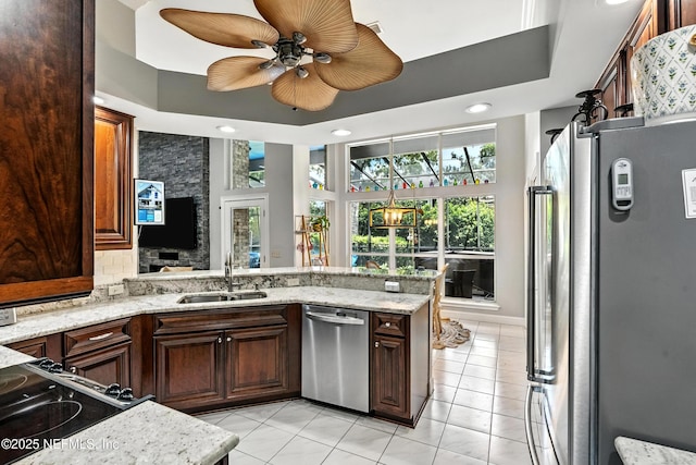 12921 Jupiter Hills Cir N, Jacksonville, FL 32225 - kitchen featuring appliances with stainless steel finishes, light tile patterned floors, a peninsula, ceiling fan, and light stone countertops