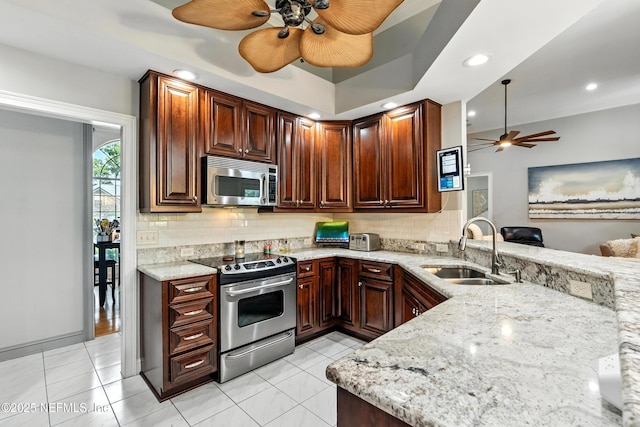 12921 Jupiter Hills Cir N, Jacksonville, FL 32225 - kitchen featuring appliances with stainless steel finishes, a ceiling fan, backsplash, light stone countertops, and a peninsula