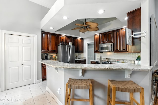 12921 Jupiter Hills Cir N, Jacksonville, FL 32225 - kitchen with appliances with stainless steel finishes, a ceiling fan, backsplash, a peninsula, and a breakfast bar