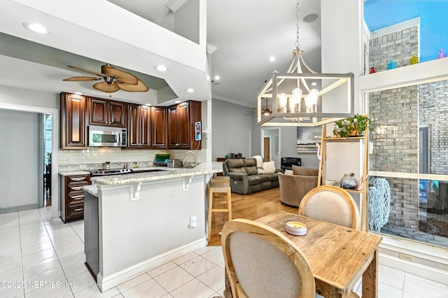 12921 Jupiter Hills Cir N, Jacksonville, FL 32225 - kitchen featuring appliances with stainless steel finishes, a breakfast bar area, tasteful backsplash, ceiling fan, and dark brown cabinetry