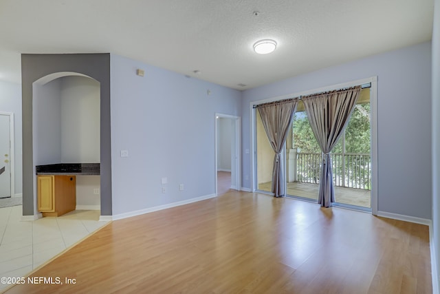 8601 Beach Blvd Unit 1008, Jacksonville, FL 32216 - empty room with light wood-style floors, arched walkways, and a textured ceiling