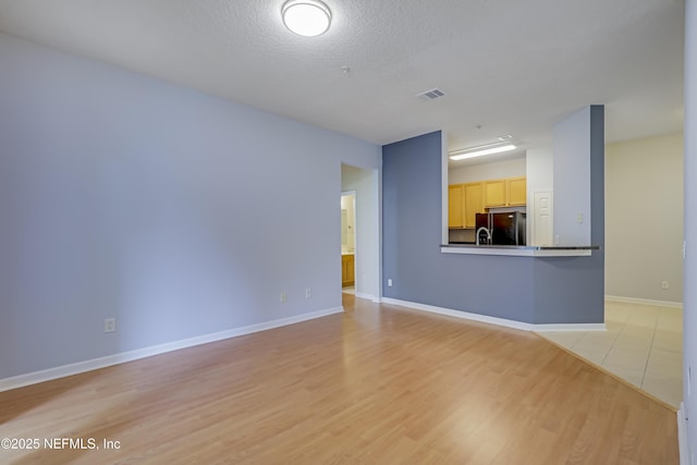 8601 Beach Blvd Unit 1008, Jacksonville, FL 32216 - unfurnished living room featuring light wood-style floors and a textured ceiling