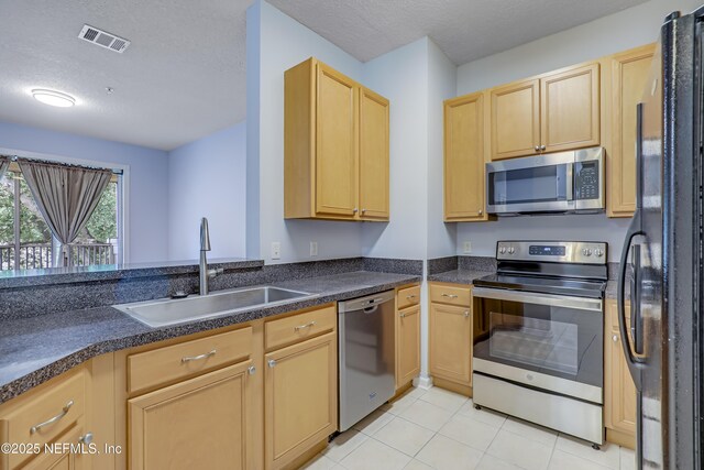 8601 Beach Blvd Unit 1008, Jacksonville, FL 32216 - kitchen with stainless steel appliances, light brown cabinetry, dark countertops, light tile patterned floors, and a textured ceiling