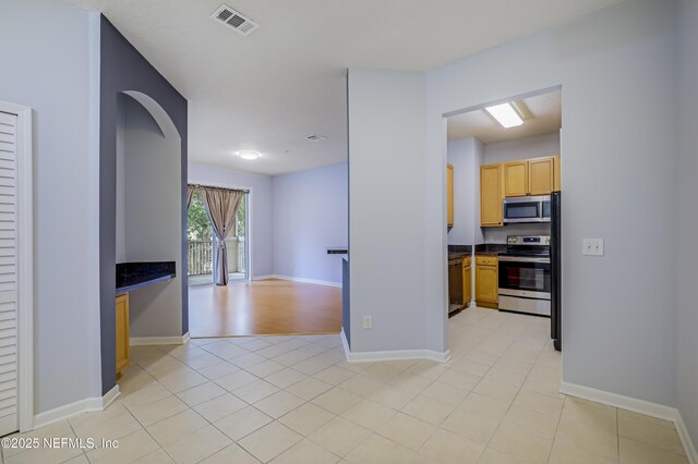8601 Beach Blvd Unit 1008, Jacksonville, FL 32216 - kitchen featuring appliances with stainless steel finishes, dark countertops, arched walkways, light brown cabinets, and open floor plan
