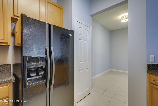 8601 Beach Blvd Unit 1008, Jacksonville, FL 32216 - kitchen featuring black fridge with ice dispenser, light tile patterned floors, and dark countertops