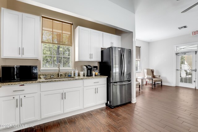 8601 Beach Blvd Unit 1008, Jacksonville, FL 32216 - kitchen with freestanding refrigerator, black microwave, light stone countertops, and white cabinetry