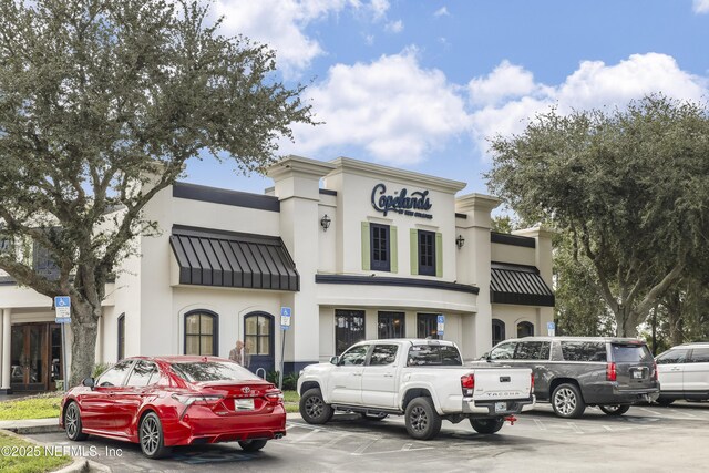 8601 Beach Blvd Unit 1008, Jacksonville, FL 32216 - view of front of home featuring a standing seam roof, uncovered parking, stucco siding, and a metal roof