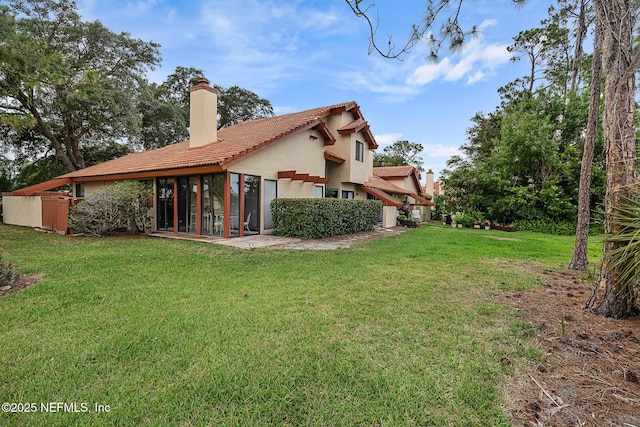55 Village Cir, Palm Coast, FL 32164 - back of house featuring a chimney, stucco siding, a sunroom, a tiled roof, and a yard