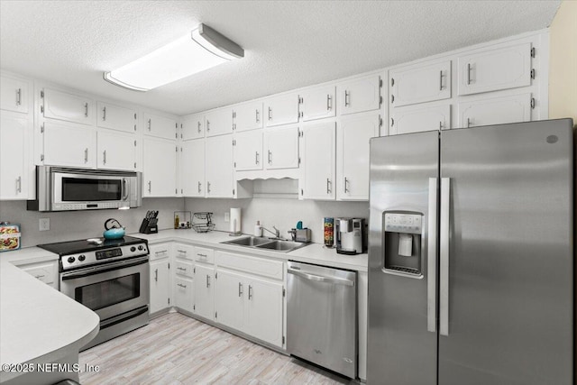 1506 Strand St, Neptune Beach, FL 32266 - kitchen featuring appliances with stainless steel finishes, white cabinets, a textured ceiling, light wood finished floors, and light countertops