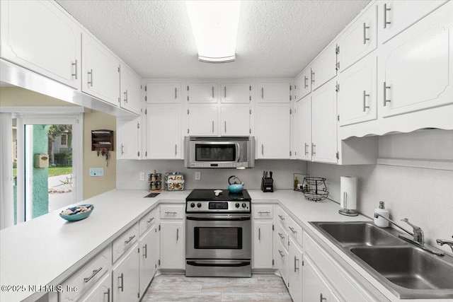 1506 Strand St, Neptune Beach, FL 32266 - kitchen with stainless steel appliances, a textured ceiling, white cabinetry, light wood-type flooring, and light countertops