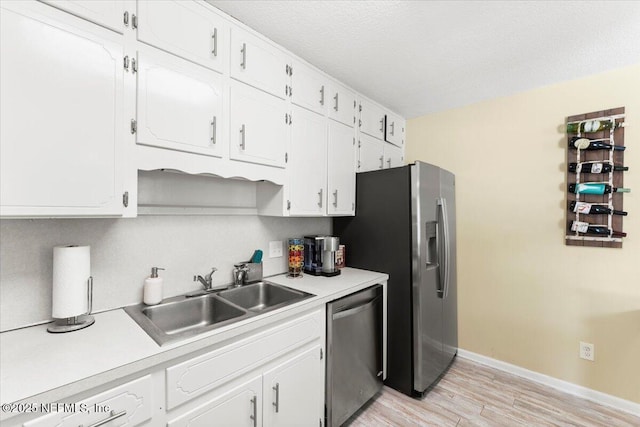 1506 Strand St, Neptune Beach, FL 32266 - kitchen featuring stainless steel appliances, light wood-type flooring, white cabinets, light countertops, and a textured ceiling