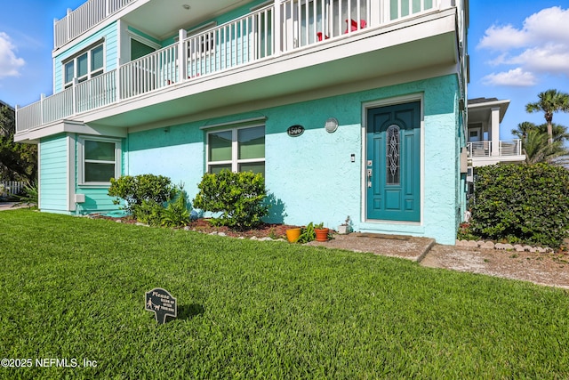 1506 Strand St, Neptune Beach, FL 32266 - property entrance with a balcony, a lawn, and stucco siding