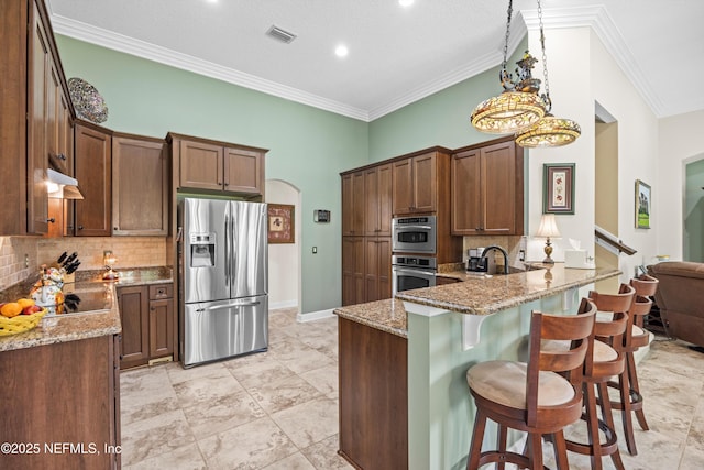 641 Donald Ross Way, Saint Augustine, FL 32092 - kitchen with stainless steel appliances, under cabinet range hood, light stone counters, backsplash, and crown molding
